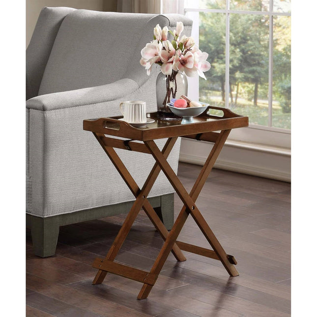 Wooden tray table with a cup, saucer, and flowers in a vase on a gray sofa.