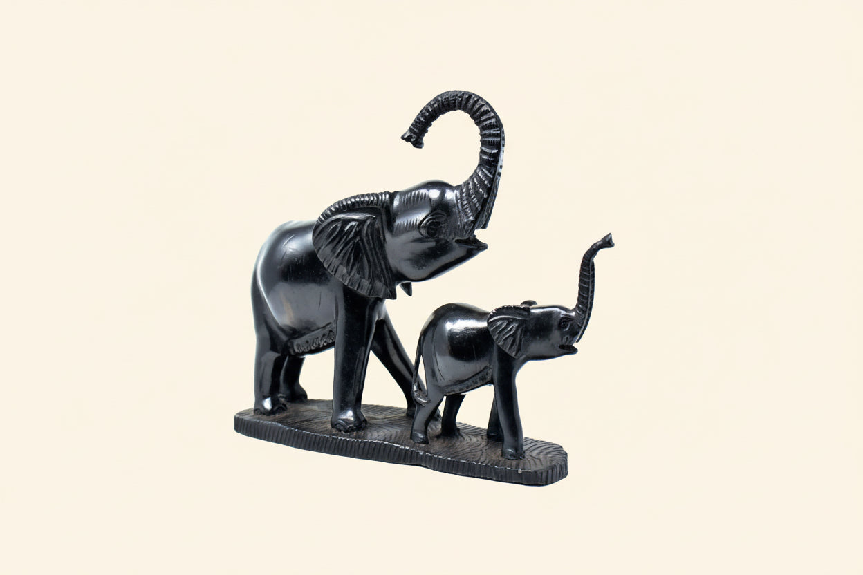 Black metal sculpture of two elephants on a white background