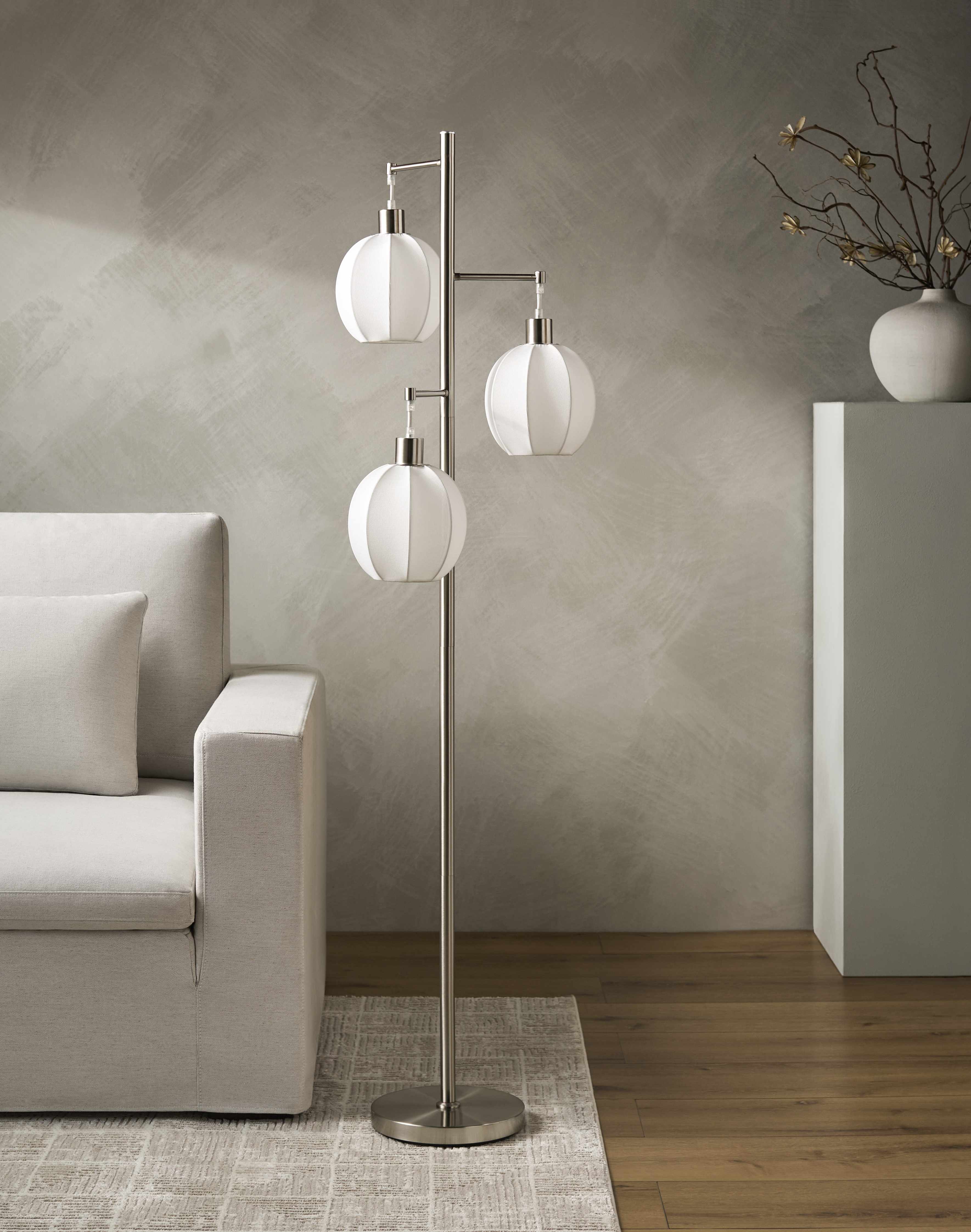 Modern floor lamp with three spherical lights in a living room setting.