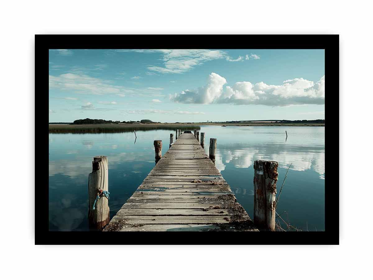 Wooden dock extending into a calm body of water with a clear sky.
