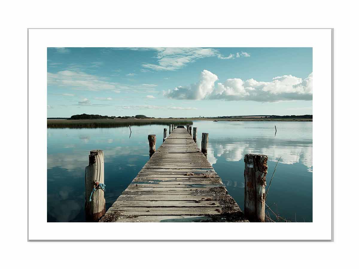 Wooden dock extending into a calm body of water with a clear sky.