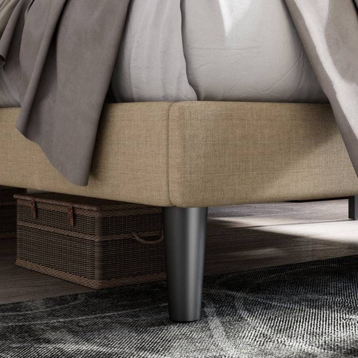 Close-up of a bed with beige bedding and a woven basket underneath.