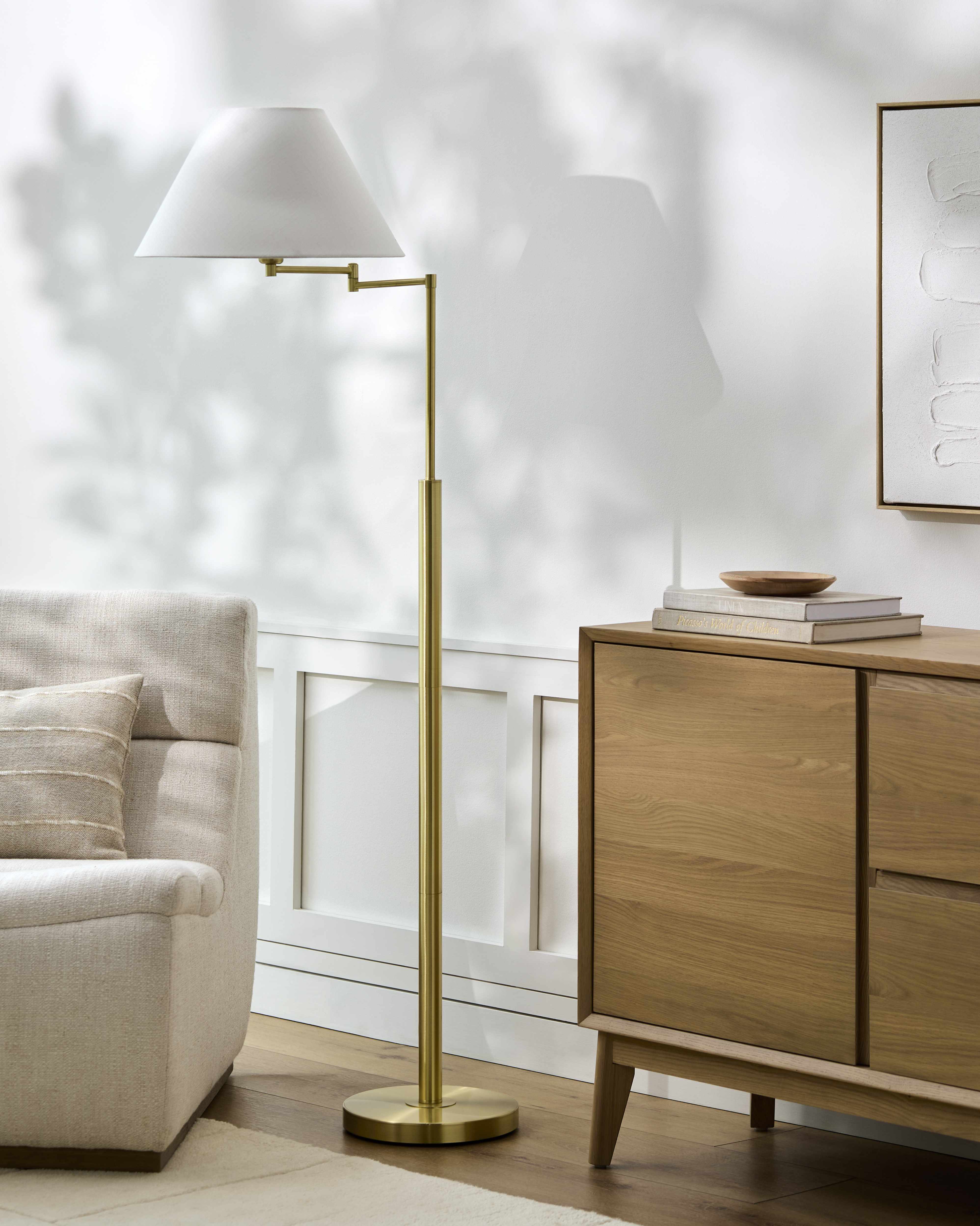 Modern living room with a gold floor lamp, wooden sideboard, and beige sofa.