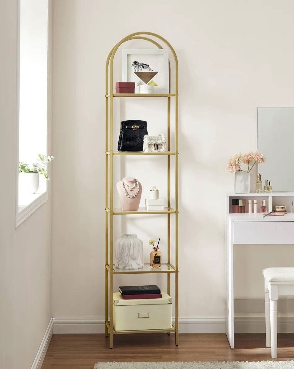 Gold metal bookshelf with decorative items on a white background