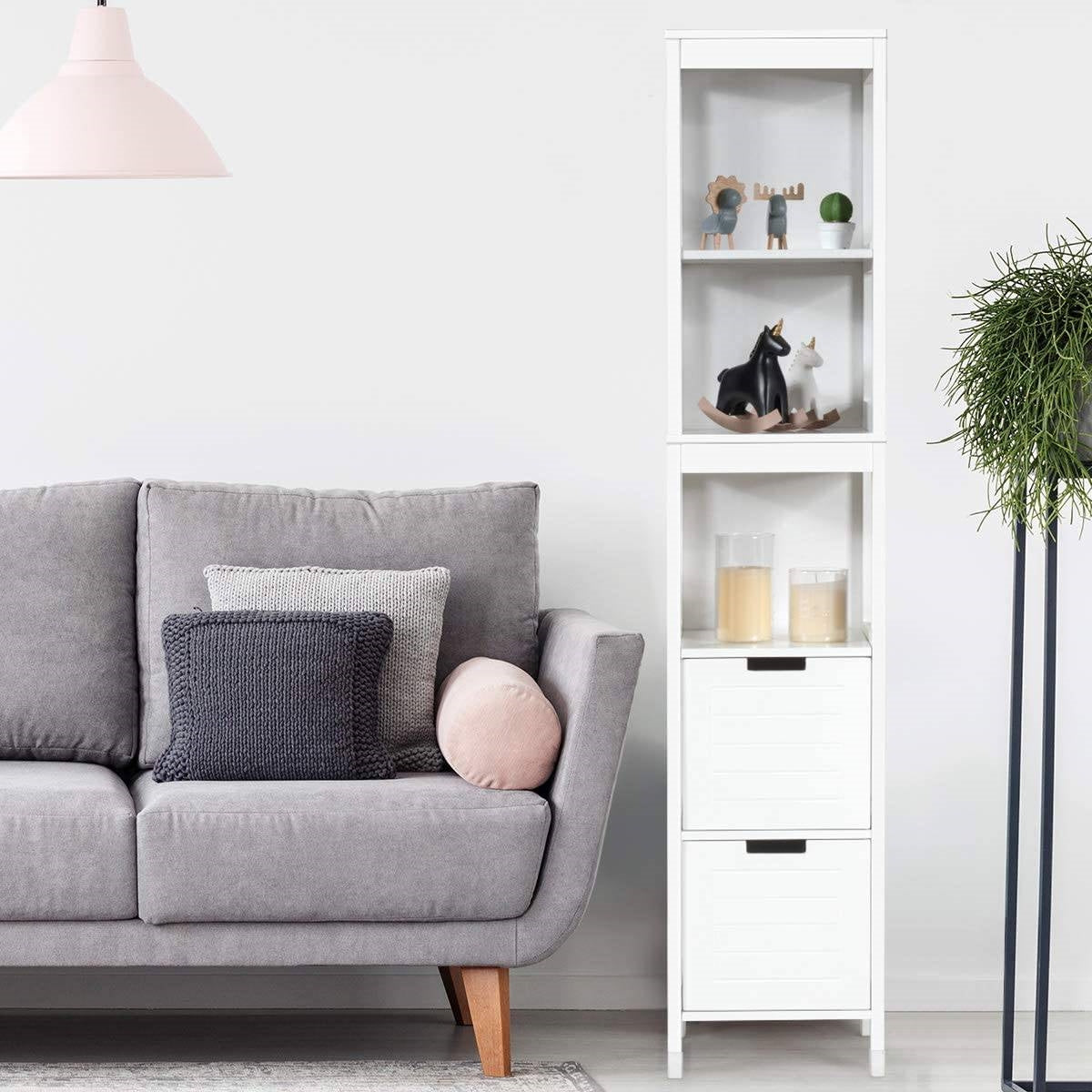 Gray sofa with decorative pillows in a living room setting with a white bookshelf and plant.