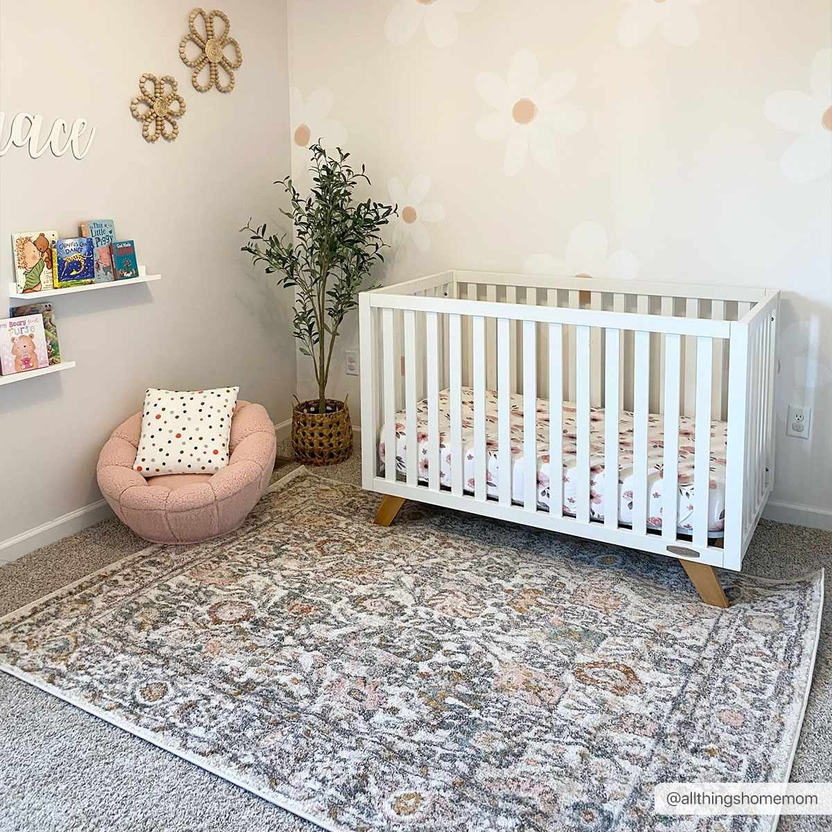 Nursery room with a white crib, patterned rug, and decorative elements.
