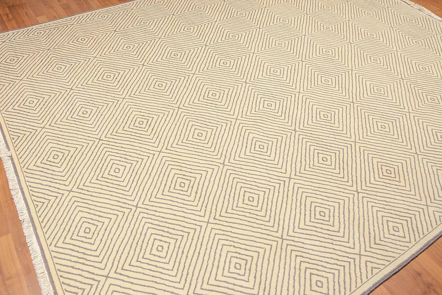 Beige area rug with geometric pattern on a wooden floor
