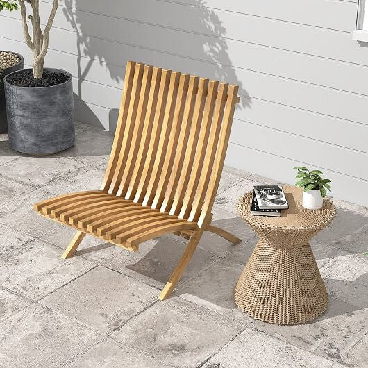 Wooden lounge chair and woven side table on a stone patio with plants.