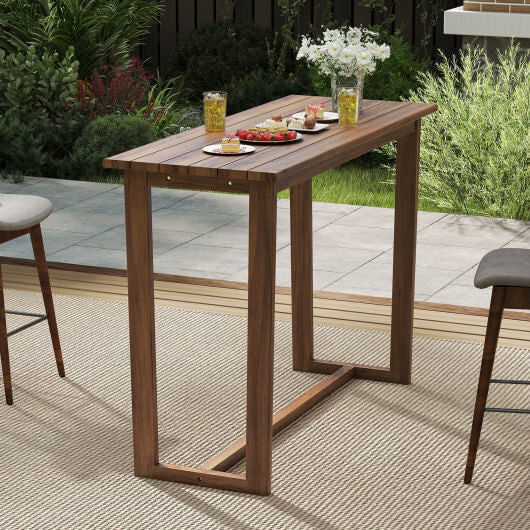 Wooden outdoor bar table with stools and a small tablecloth in a garden setting