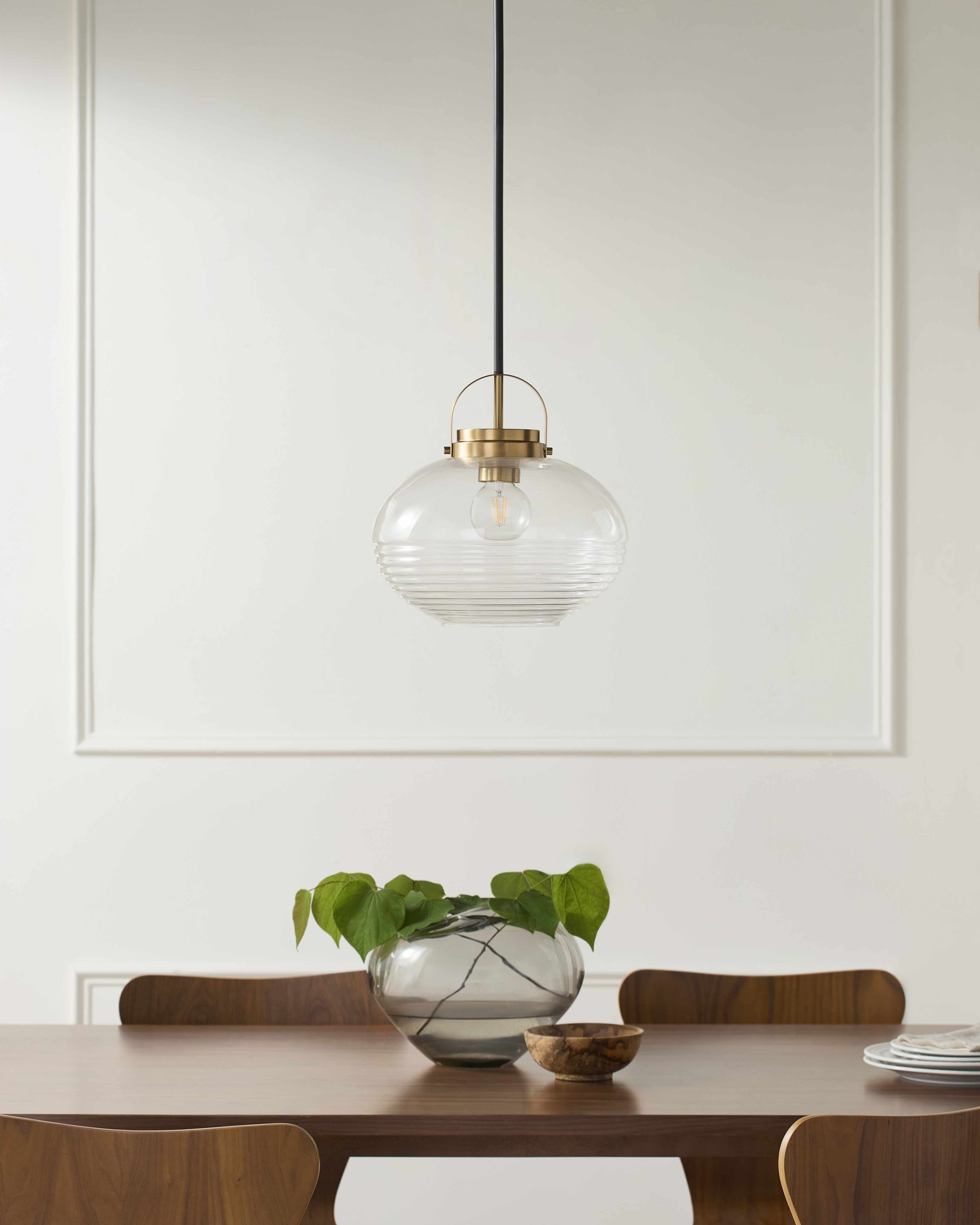 Dining room with a glass pendant light, table, chairs, and decorative items.