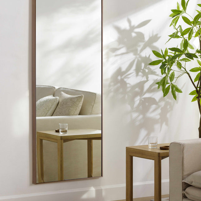 Large floor mirror in a room with a couch, coffee table, and plant