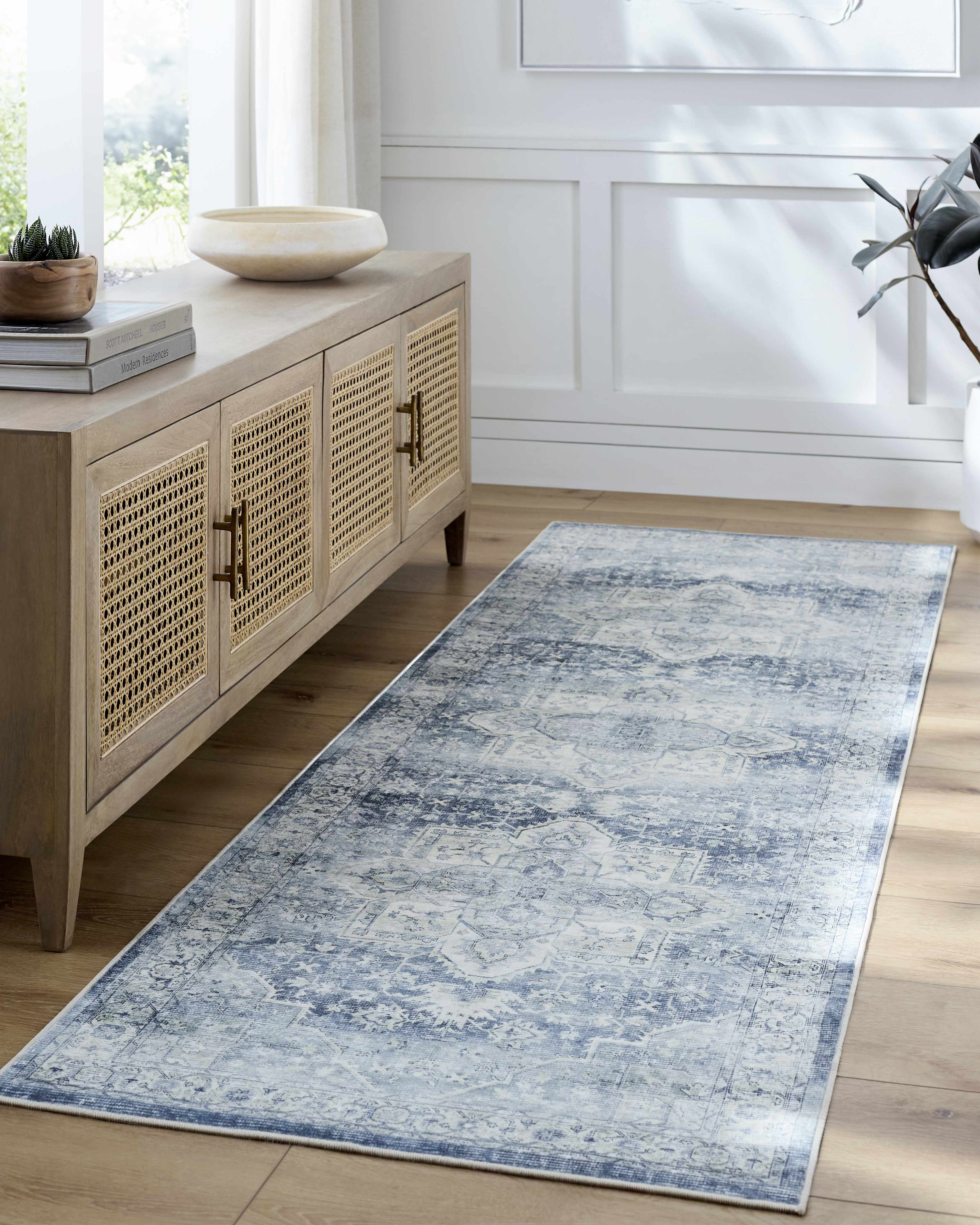 Long blue and white patterned rug on a wooden floor in a room with a wooden sideboard.