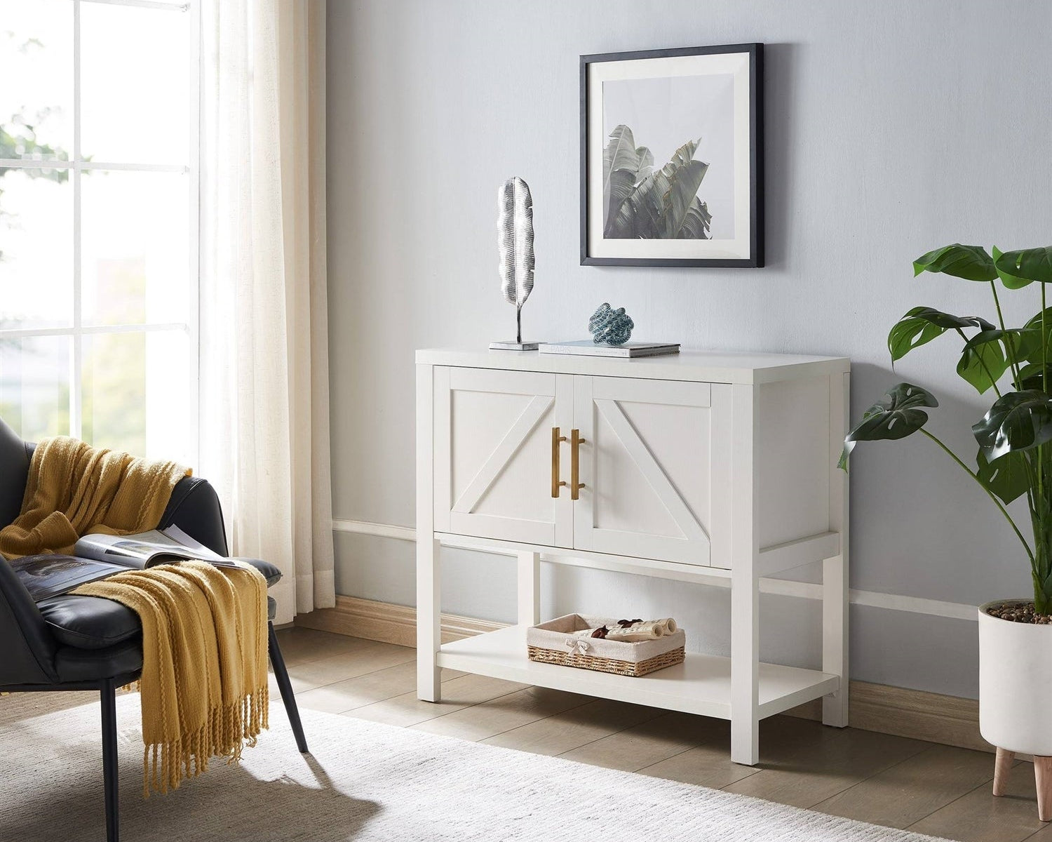 White side table with gold handles in a room with a gray wall, plant, and chair with a yellow blanket.