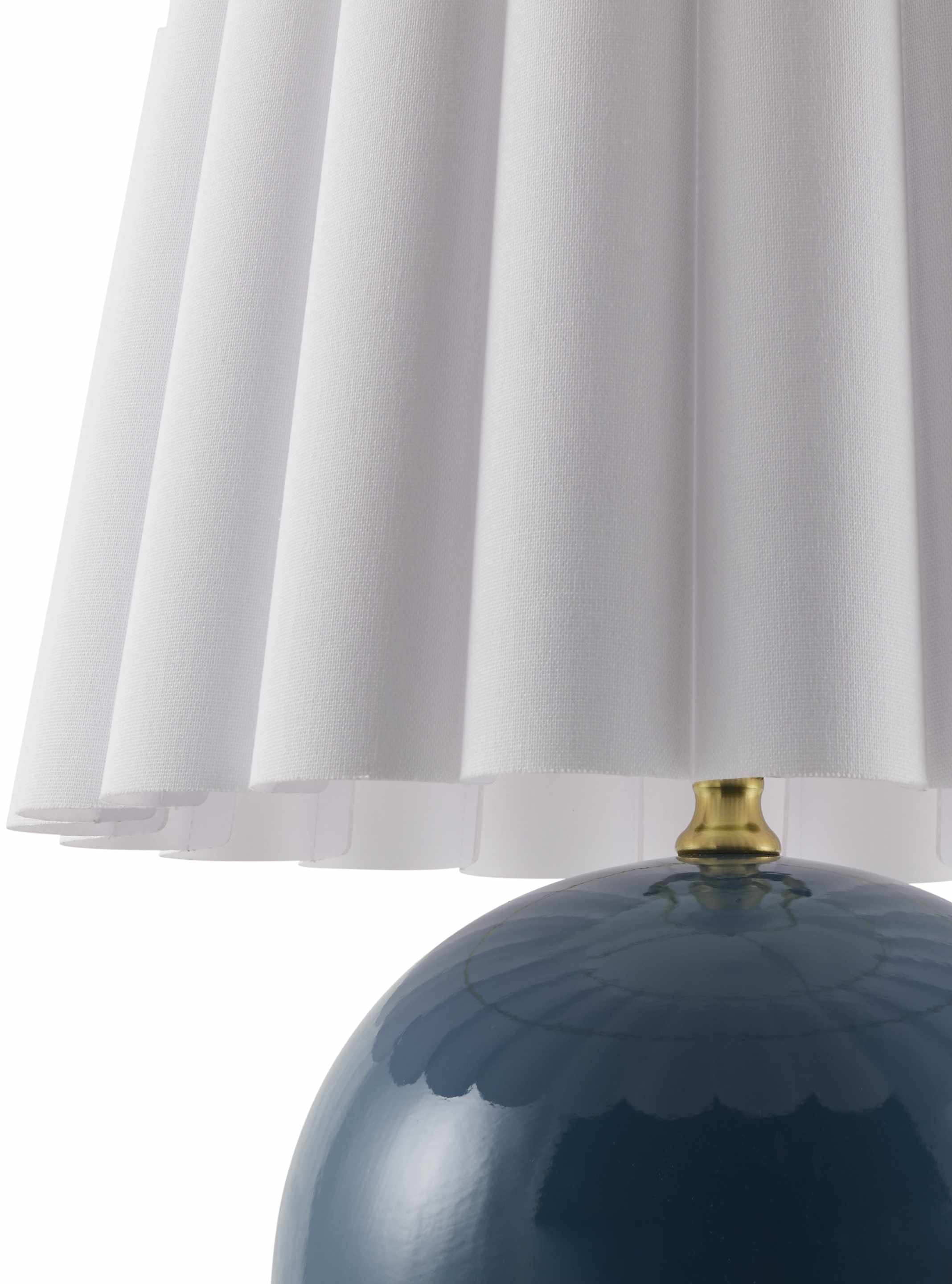 Blue lamp with a white pleated shade on a white background