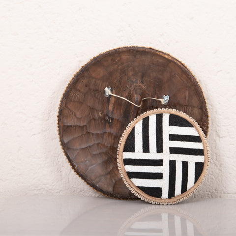 Black and white patterned hoop earring on a wooden stand against a white background