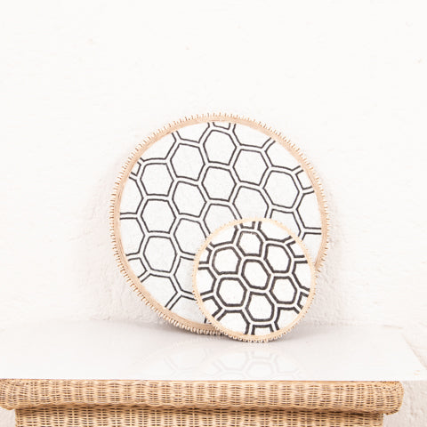 Two circular coasters with a geometric pattern on a white surface.
