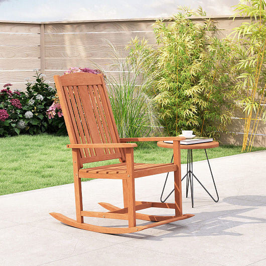Wooden rocking chair on a patio with a garden background