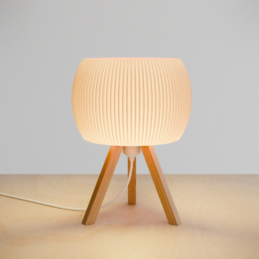Table lamp with wooden legs and ribbed design on a neutral background