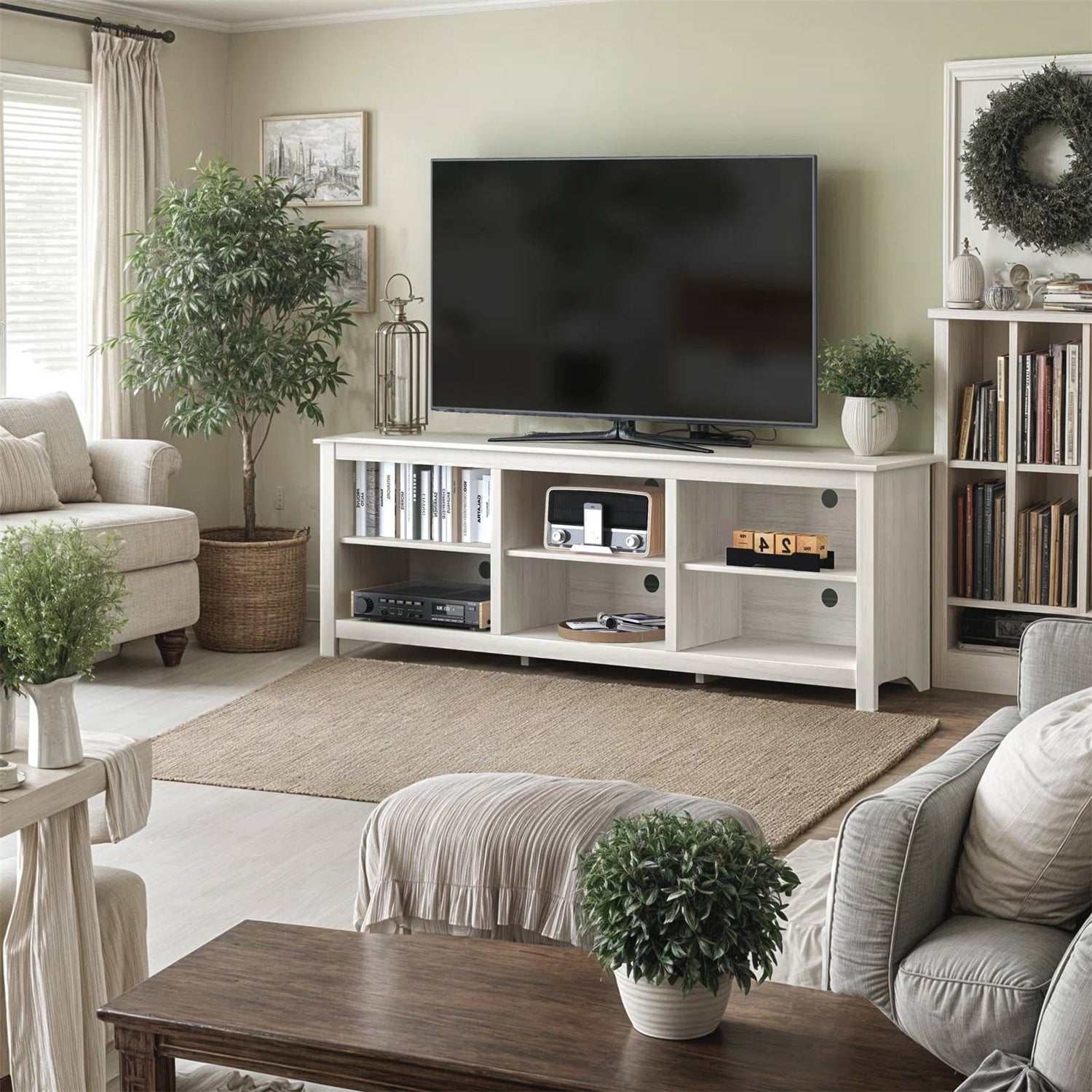 Living room with a TV on a white entertainment console, books, and decorative items.
