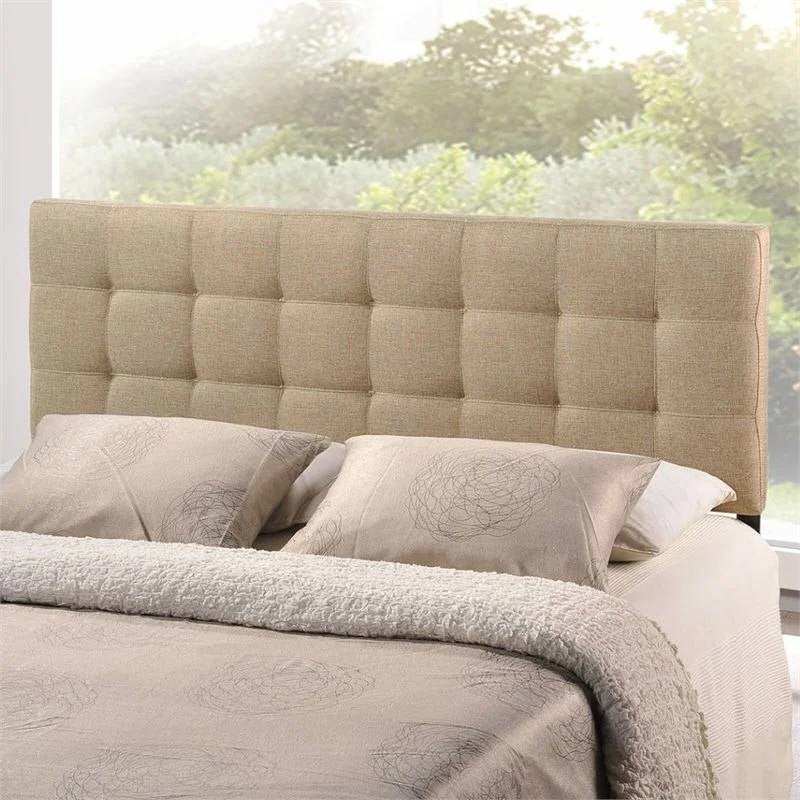Beige upholstered headboard with bedding and pillows against a blurred outdoor background