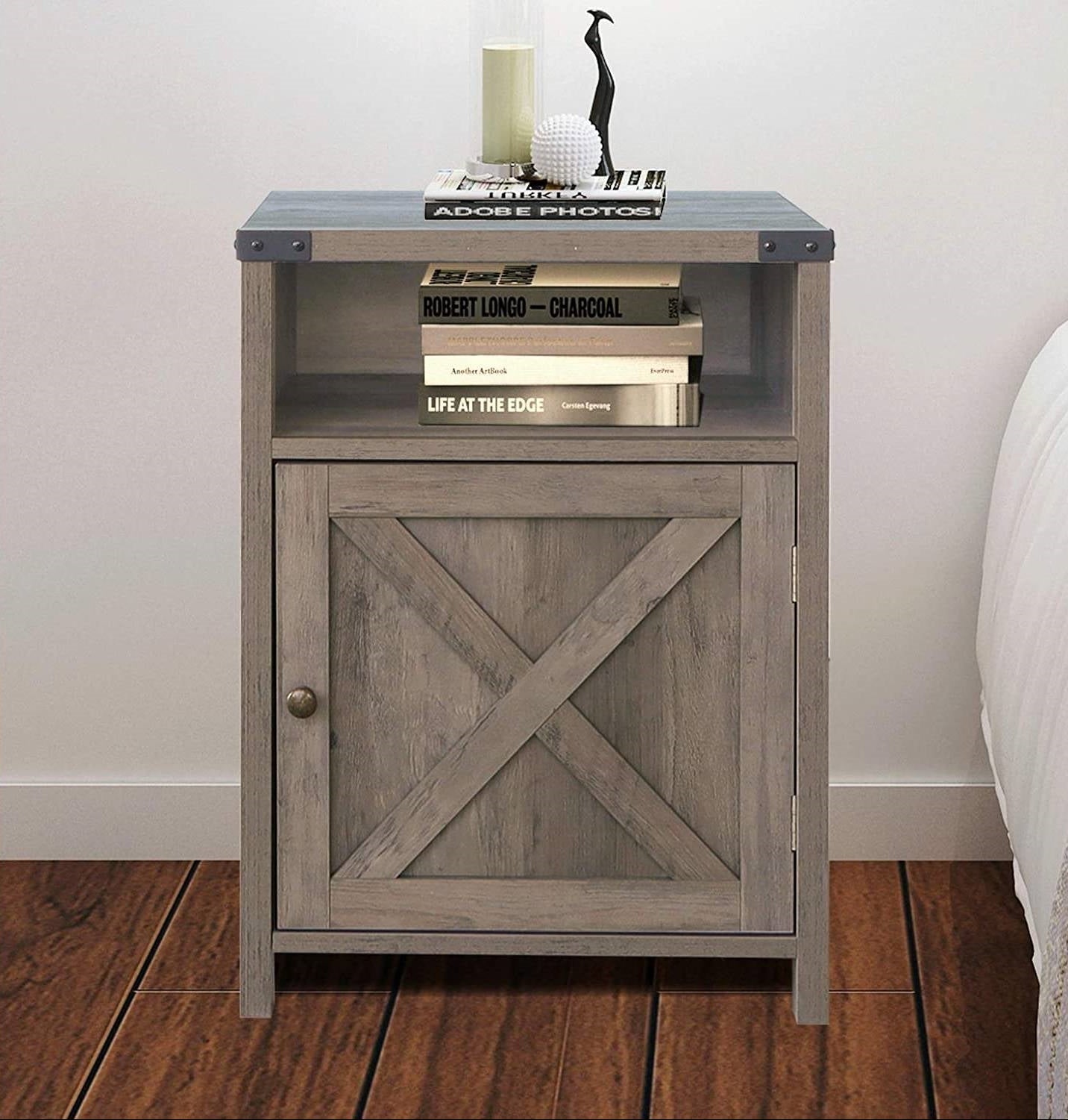 Wooden nightstand with a cabinet and open shelf against a white wall.