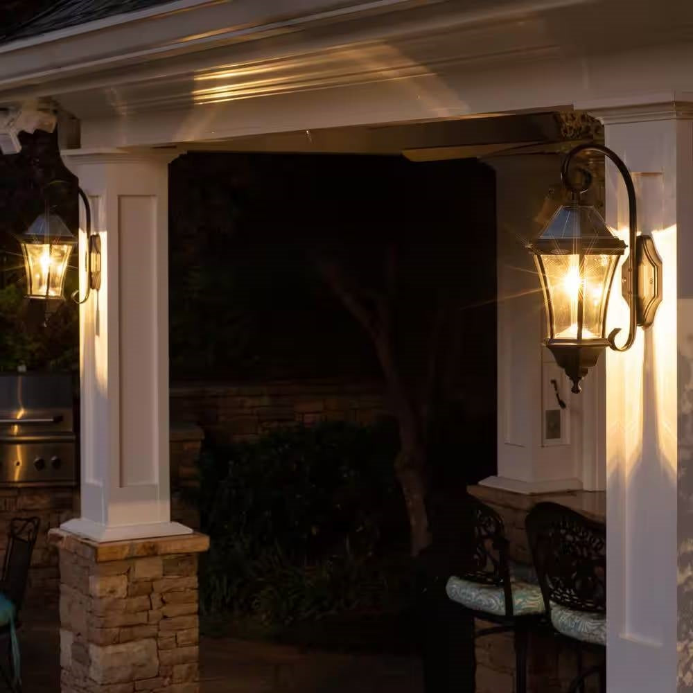 Outdoor patio area with a fireplace and wall-mounted lanterns at night.
