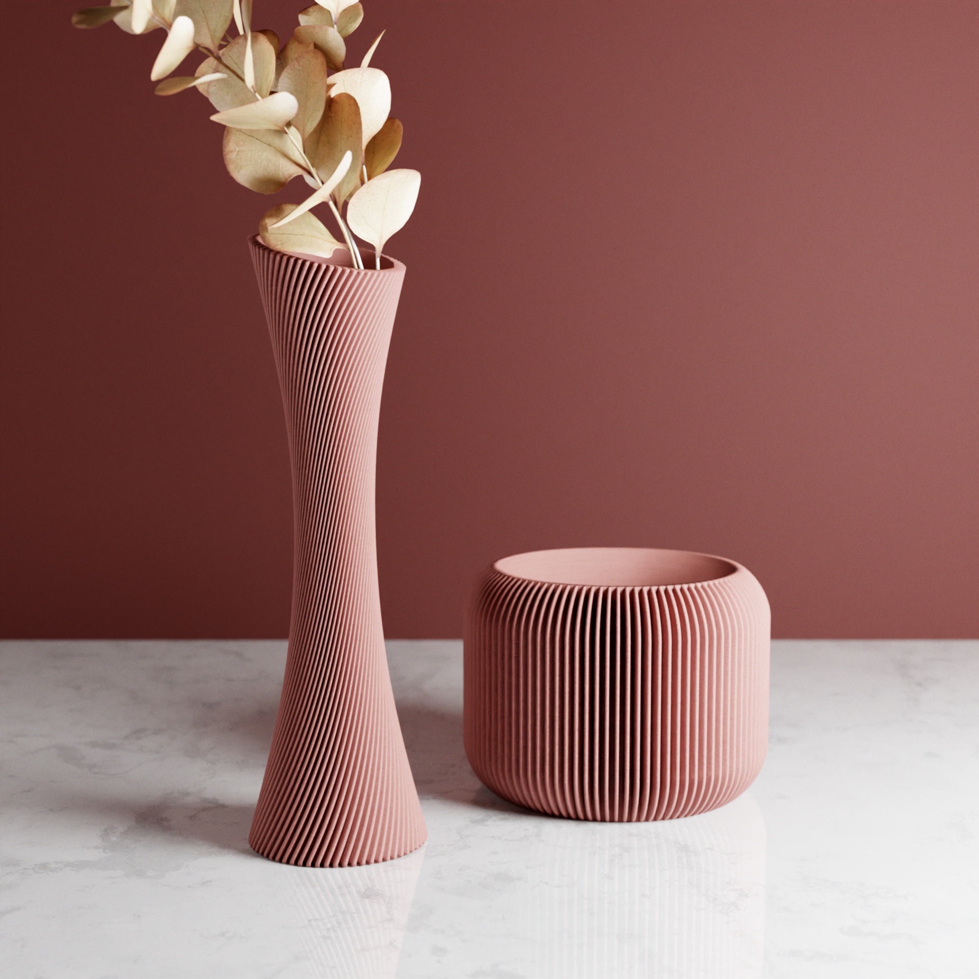 Two pink textured vases on a marble surface with a maroon background