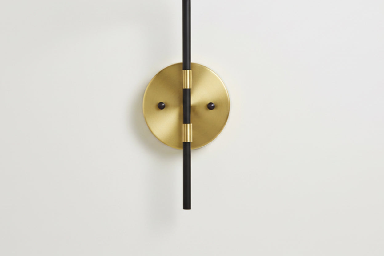 Gold wall-mounted light fixture with black cable on a white background