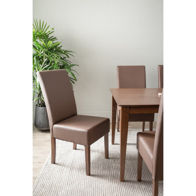 Dining room with brown chairs and a wooden table, featuring a plant in the background.