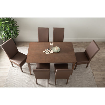Dining table set with six brown chairs in a room with a plant and rug.