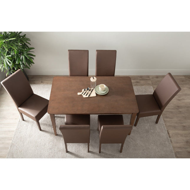 Dining table set with six brown chairs in a room with a plant and rug.