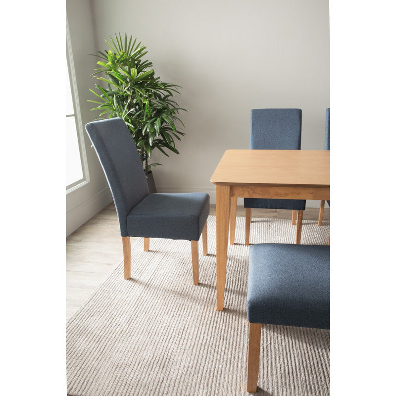 Dining room with blue chairs and a wooden table, featuring a plant in the background.