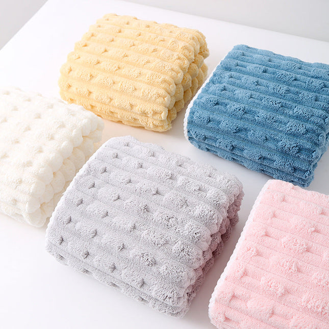 Five folded textured towels in yellow, blue, white, pink, and gray on a light surface.