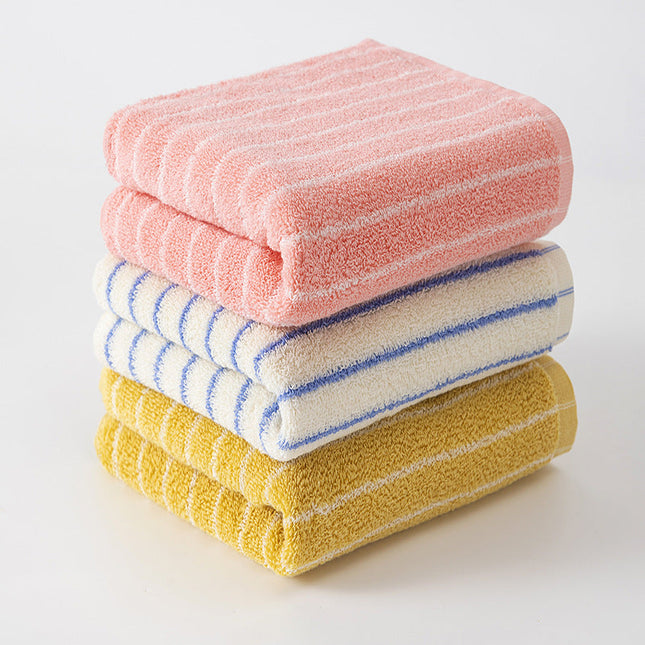 Stack of three striped towels in pink, white with blue stripes, and yellow with white stripes on a light background.
