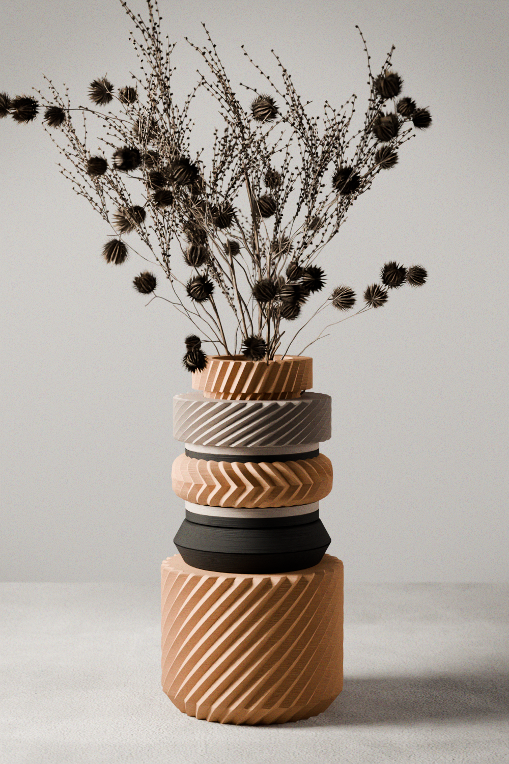 Stack of textured vases with dried plants on a neutral background