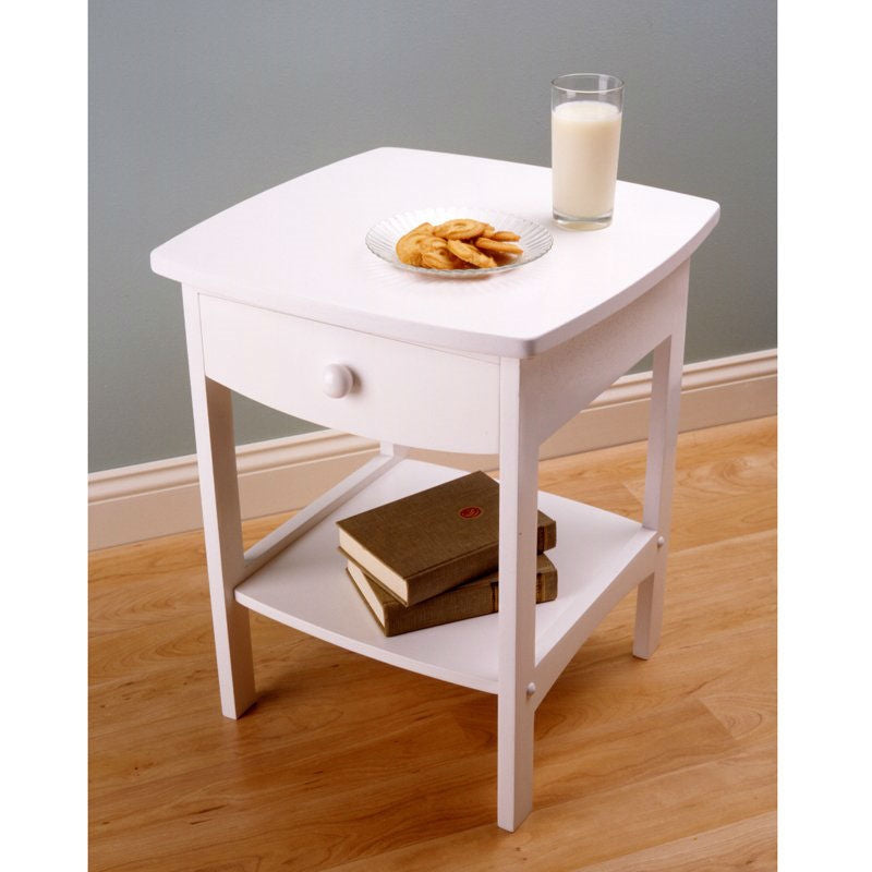 White side table with a glass of milk and cookies on a wooden floor.
