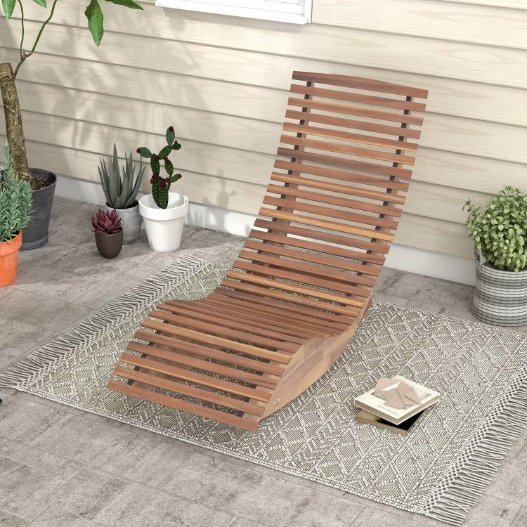 Wooden lounge chair on a patio with potted plants and a rug.