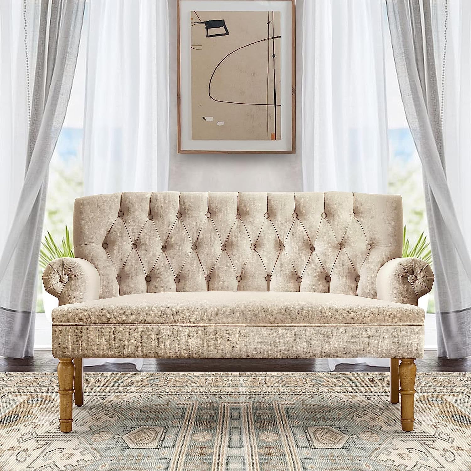 Beige tufted sofa in a living room with large windows and abstract art on the wall.