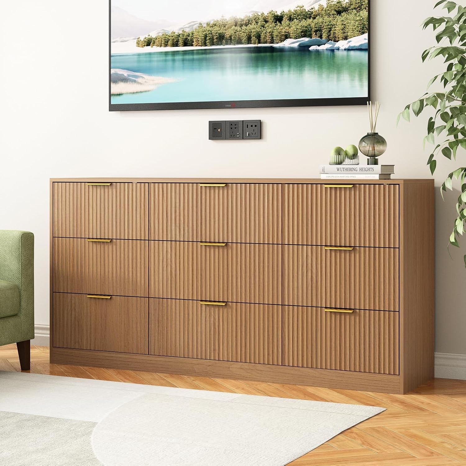Wooden dresser with gold handles in a room with a TV displaying a nature scene.