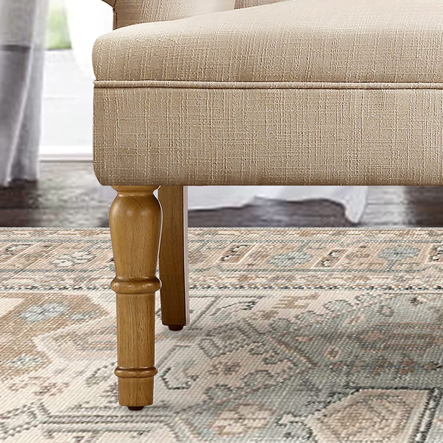 Close-up of a beige upholstered chair with wooden legs on a patterned rug.