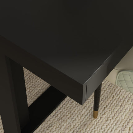 Black side table with gold leg on a textured floor