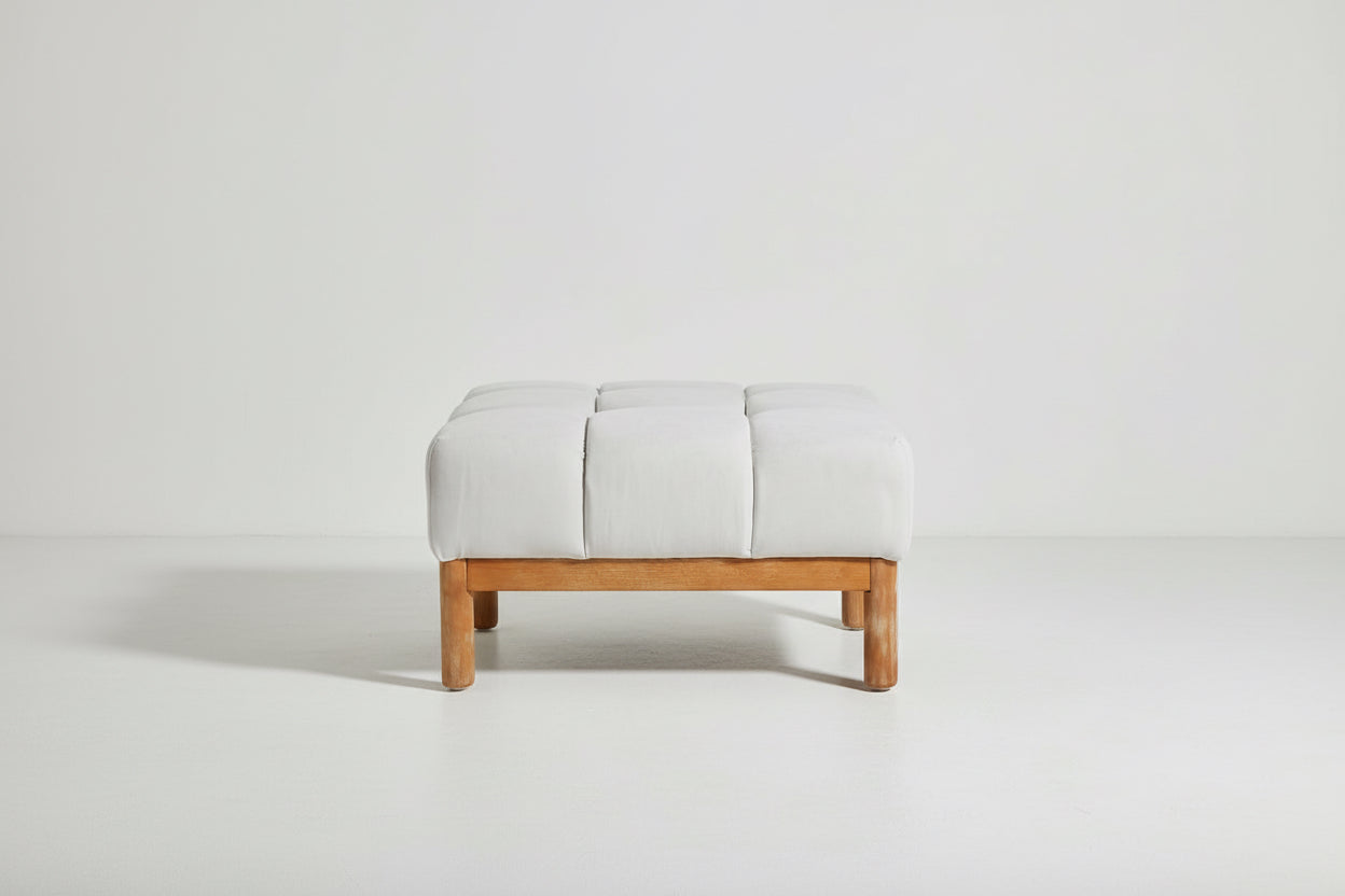 Gray upholstered ottoman with wooden legs on a white background