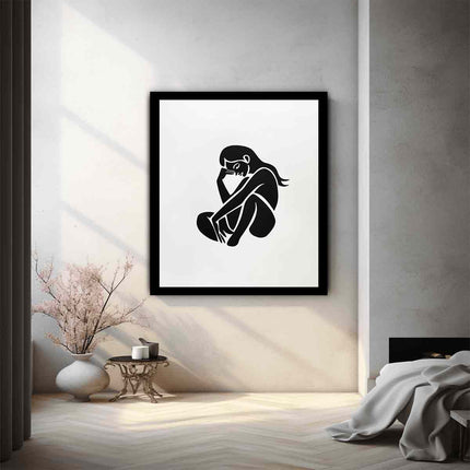 Framed black and white artwork of a sitting figure on a wall in a modern room.