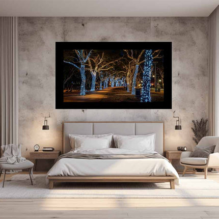 Modern bedroom with a large bed, fireplace, and wall art of illuminated trees.