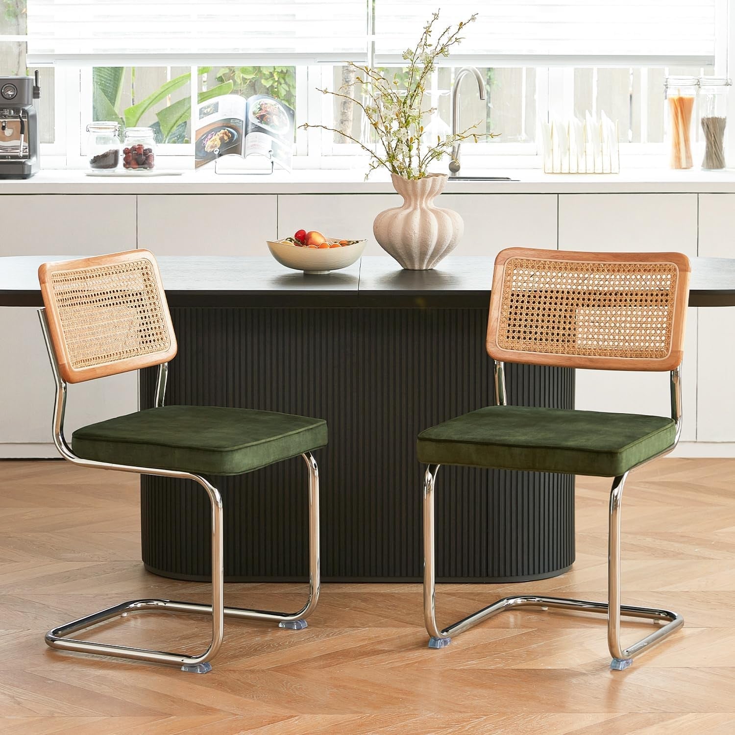 Two green cushioned chairs with wicker backs in a kitchen setting.