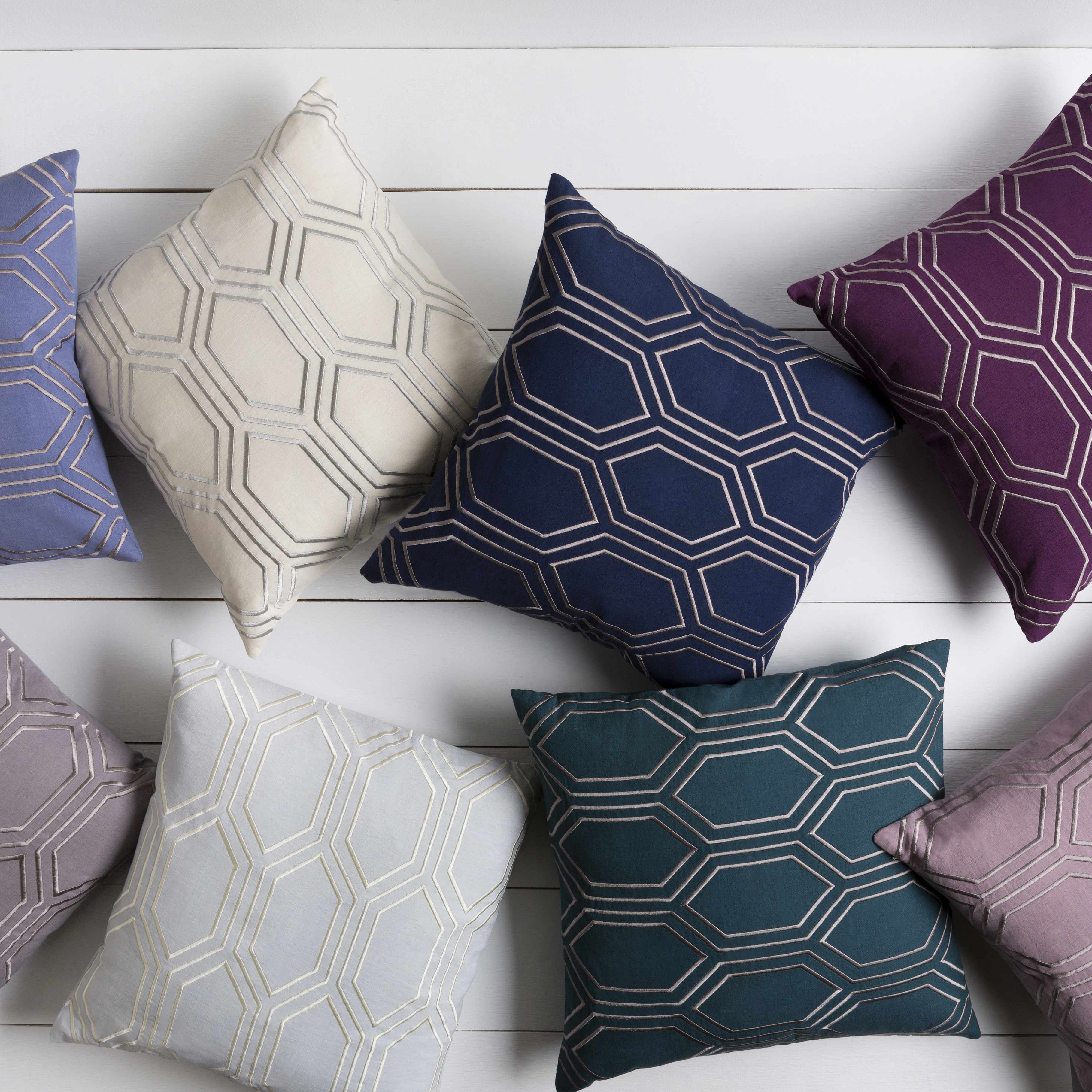 Collection of geometric patterned pillows on a white wooden surface