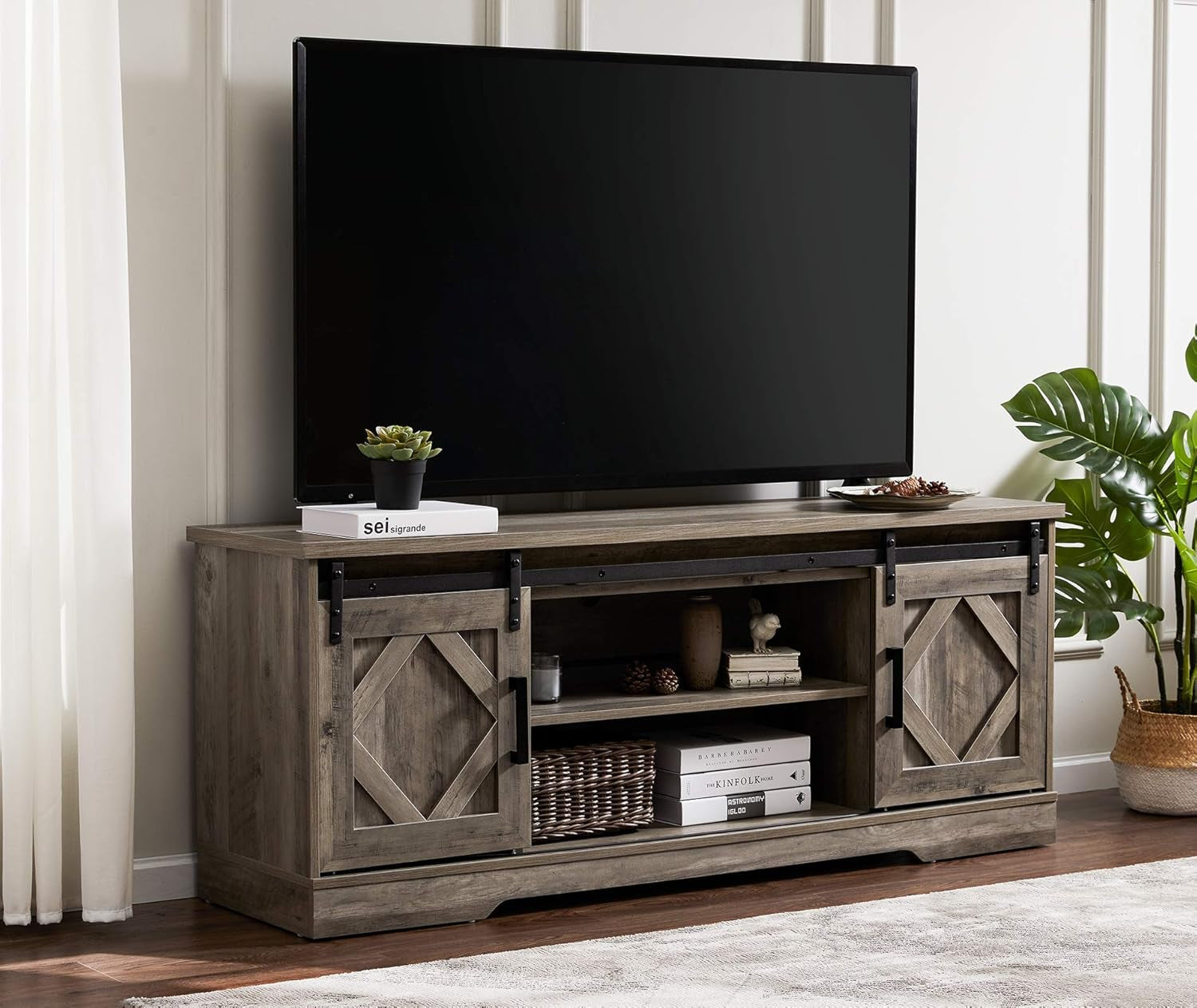 Wooden TV stand with a television mounted on it in a room with plants and decor.