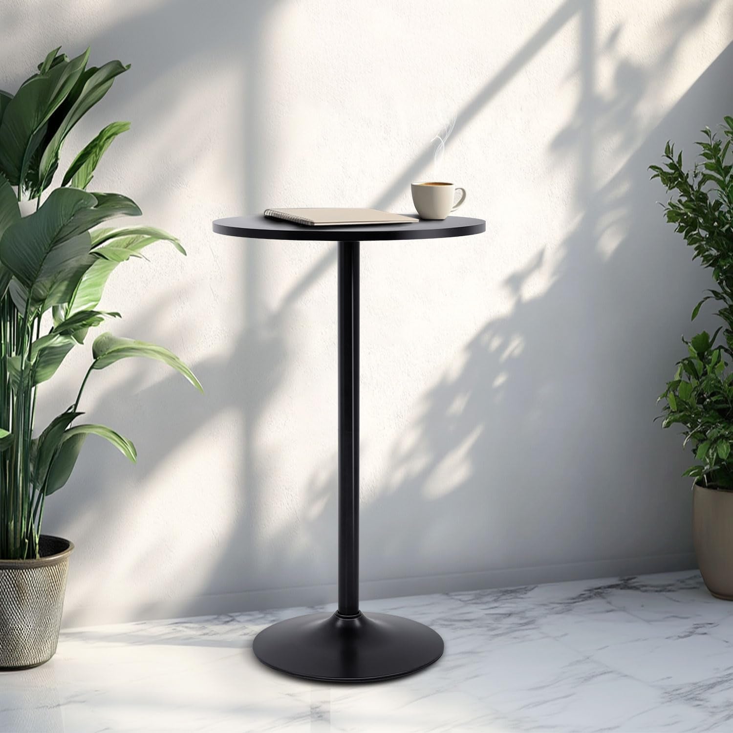 Black side table with a cup and notebook next to potted plants in a room with marble floor and white walls.