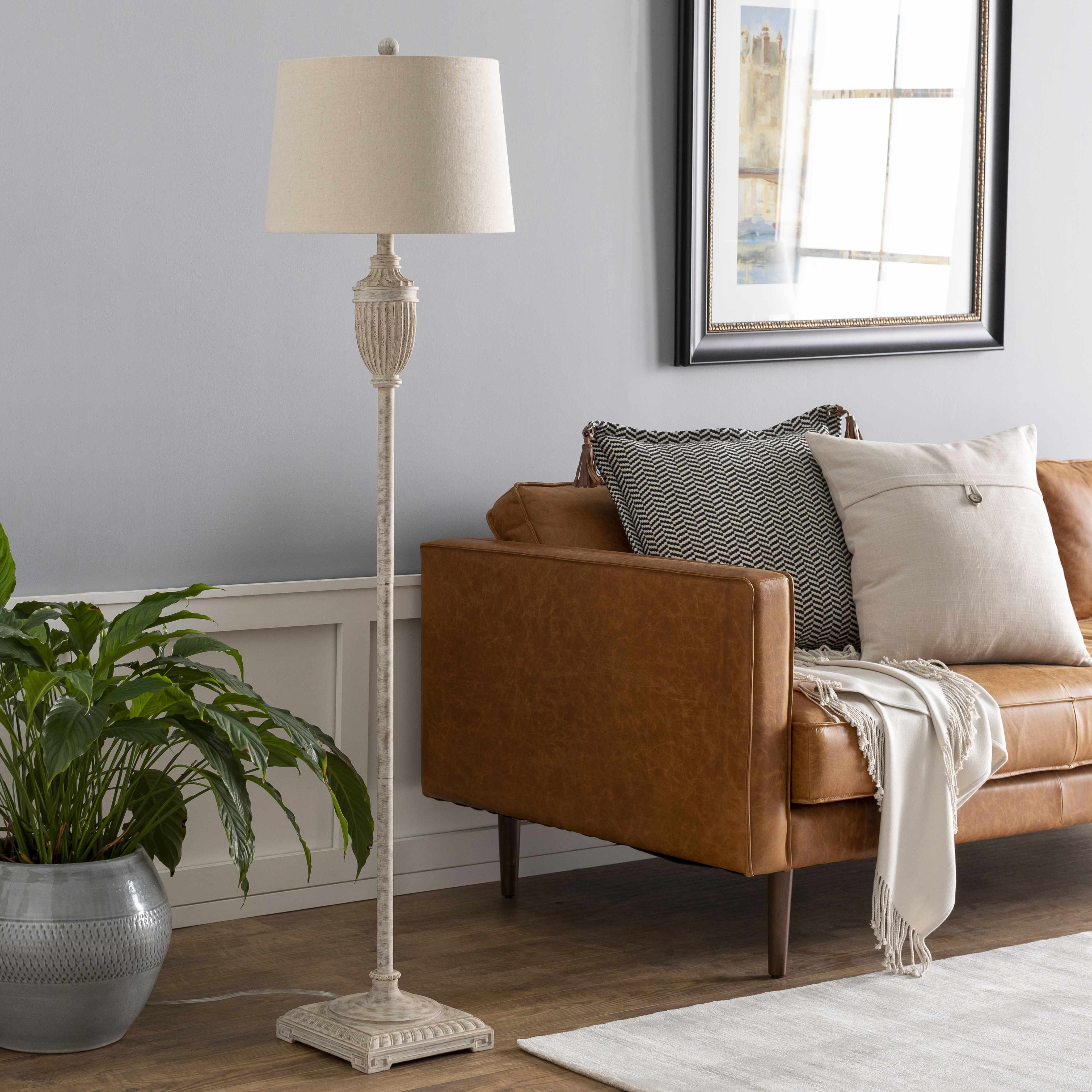 Living room with brown sofa, floor lamp, and plant