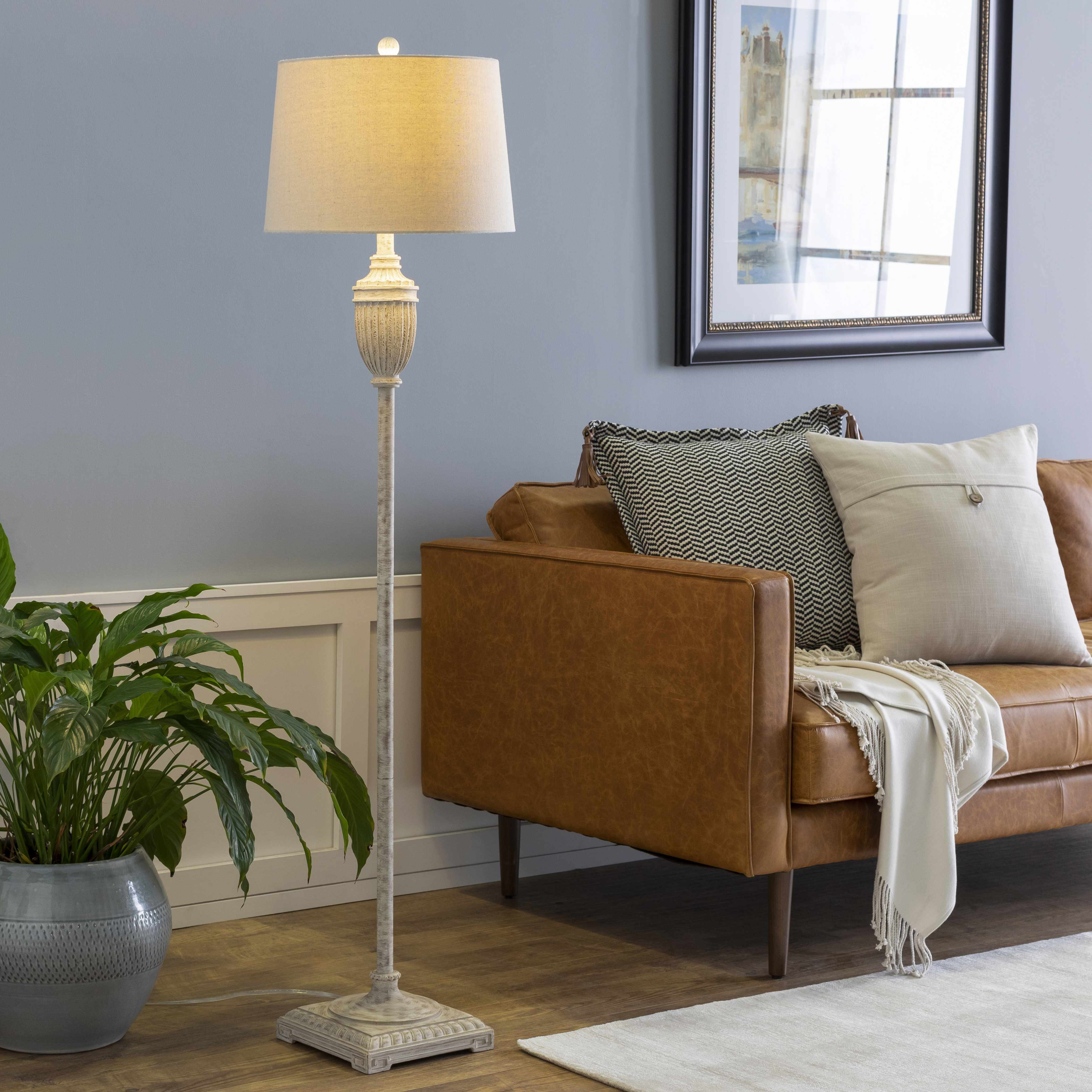 Living room with brown sofa, floor lamp, and plant
